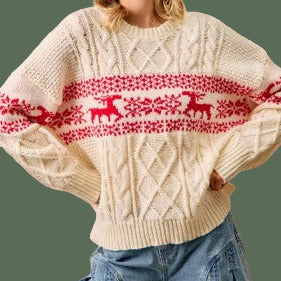 Person wearing a cream sweater with red reindeer pattern and blue jeans against a beige background